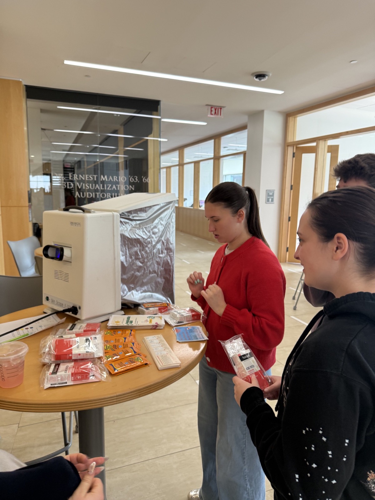 Students reviewing skin-health education materials and product samples at a PhASEd event